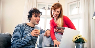 Couple de trentenaires discutant devant un ordinateur