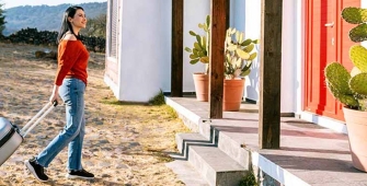 Une femme devant une maison avec une valise
