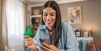 Une femme qui regarde son portable avec sa carte vitale dans la main