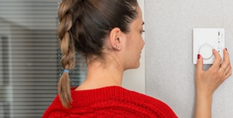 Une femme qui règle son thermostat