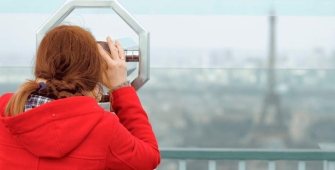 Une femme qui regarde la tour Eiffel avec des jumelles