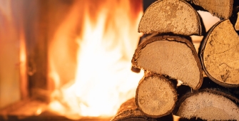 Feu de cheminée avec tas de bûches au premier plan