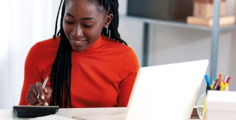 Une femme avec un stylo en train de taper sur une calculatrice