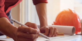 Un homme qui écrit sur un plan de chantier