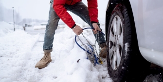 Un homme qui installe des chaines sur ses pneus