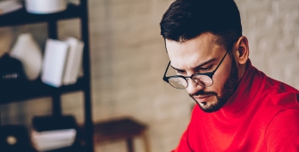 Un homme avec un pull rouge dans son bureau