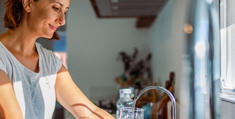 femme faisant couler l'eau du robinet de sa cuisine