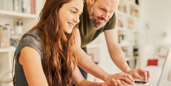 une fille et son père face à un ordinateur