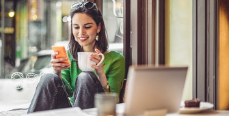 femme assise son portable et un café en mains