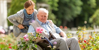 Une femme qui pousse un homme âgé en fauteuil