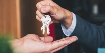 Une personne qui donne des clés des maisons dans une main