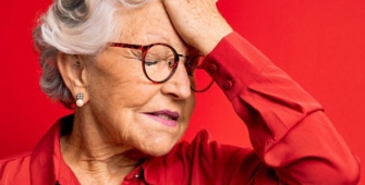 Une femme âgée qui se tient la tête 