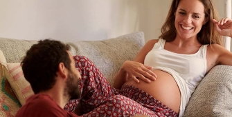 Une femme enceinte avec son homme sur un canapé