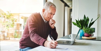 Un homme qui consulte son ordinateur dans sa cuisine