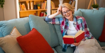 Une femme qui lit un livre dans son canapé