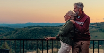 Un couple âgé regarde un coucher de soleil sur son balcon