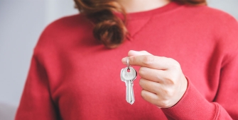 Une femme pull rouge avec une clé dans la main