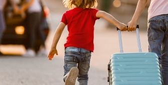 Un enfant et un adulte de dos qui tirent une valise