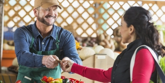 Un commerçant sourit à sa cliente sur un marché