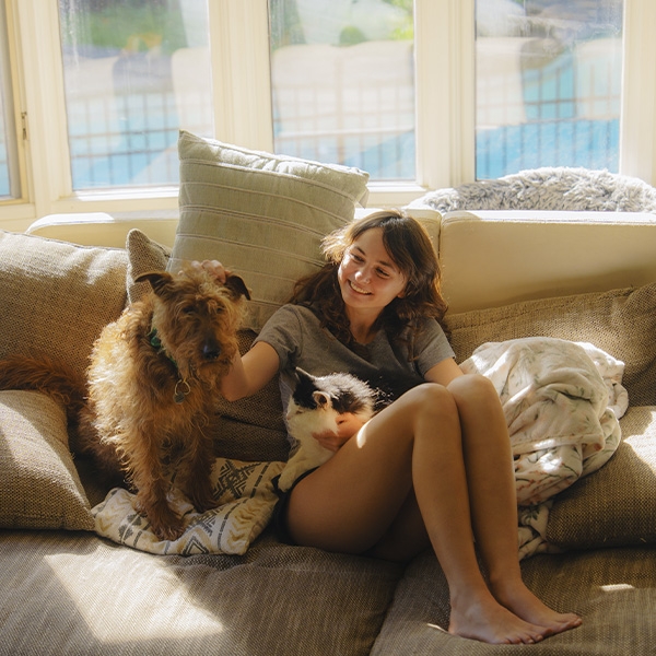 une ados avec un chien et un chat sur un canapé