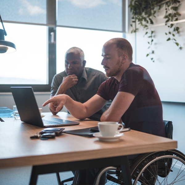 Deux homme au travail qui discutent, l'un est en fauteuil roulant