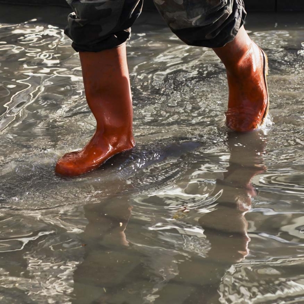 Personne marchant avec des bottes dans une rue inondée