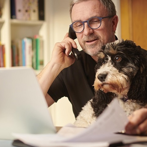 retraité au téléphone, son chien sur les genoux