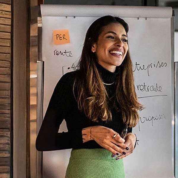Jeune femme devant un paper board où figurent les mots "retraite" et "entreprise"