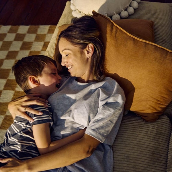 Jeune mère câlinant son fils sur un canapé brun