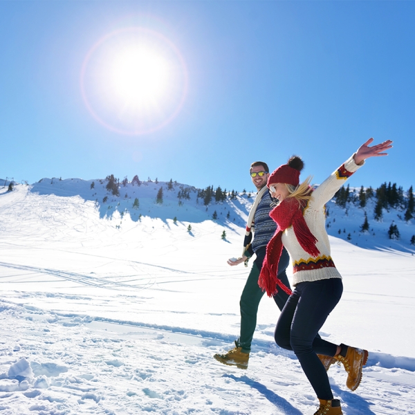 couple marchant sur la neige et sous le soleil