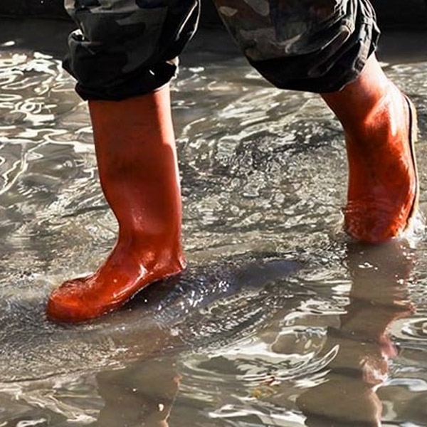 Personne marchant dans l'eau avec des bottes rouges