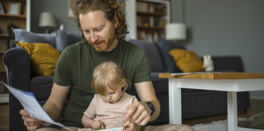 Un homme en train de lire un document avec sa fille sur ses genoux