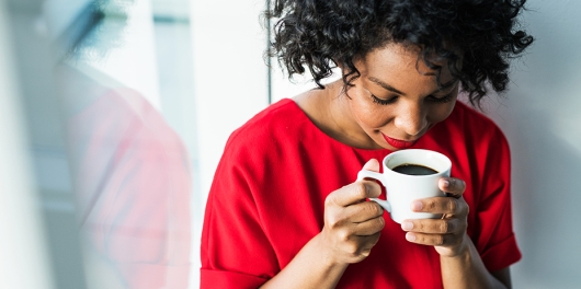 femme buvant une tasse de café à la fenêtre