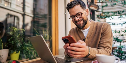 Jeune auto-entrepreneur au téléphone devant son ordinateur portable