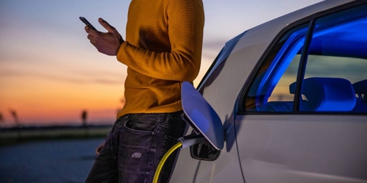 Automobiliste devant sa voiture électrique en charge à une borne