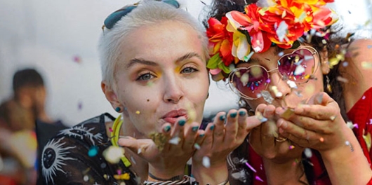 Deux jeunes femmes soufflent des paillettes lors d'un festival