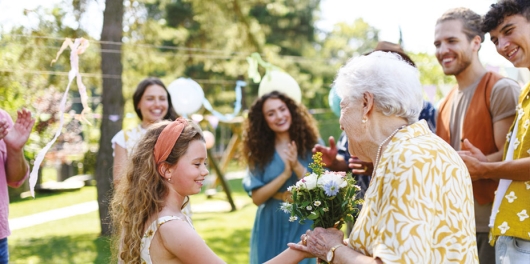 petite fille offrant un bouquet de fleurs à une dame âgée