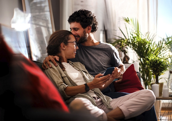 un couple sur leur canapé qui s'embrasse