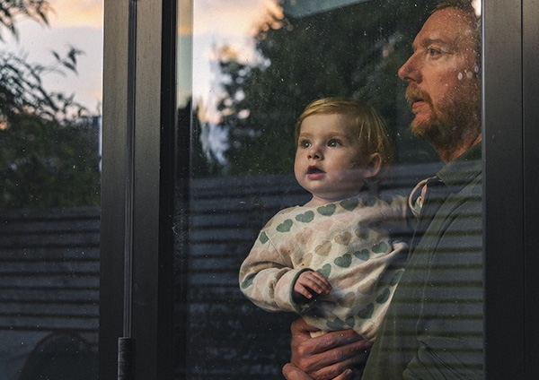 Un homme qui porte son fils et regardent par la fenêtre