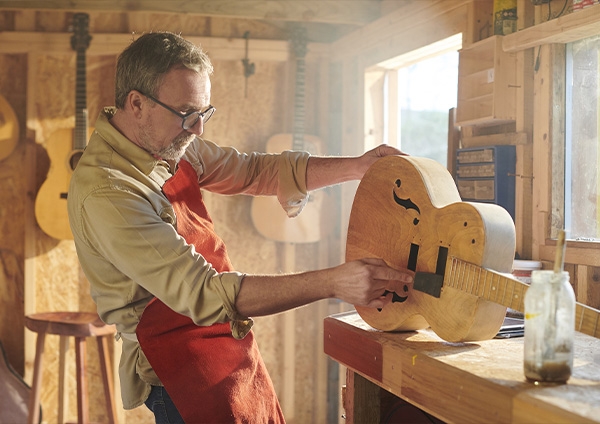 un artisan dans son atelier qui fabrique une guitare