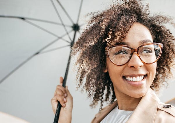 Jeune femme souriant sous son parapluie