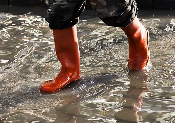 Personne marchant dans l'eau avec des bottes rouges