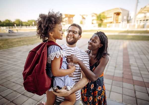 une jeune fille et ses parents devant l'école