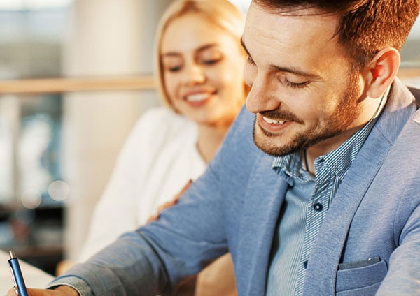 Jeune couple souriant signant des papiers