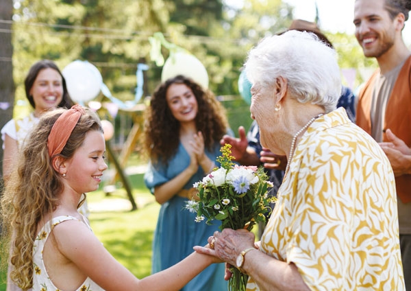 petite fille offrant un bouquet de fleurs à une dame âgée