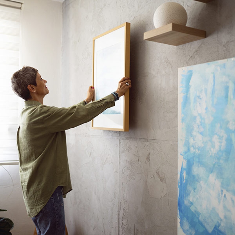 Une dame qui accroche un tableau