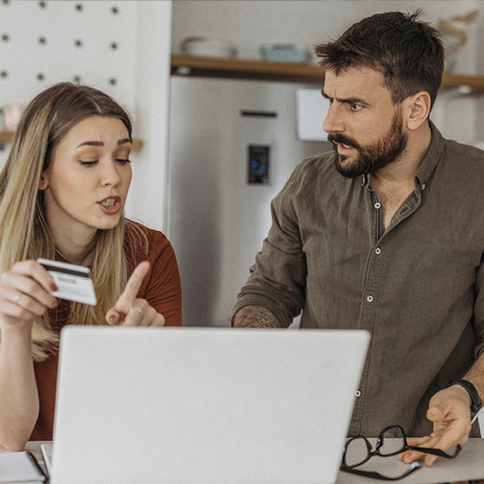 un couple qui débatent sur un achat en ligne avec une carte bancaire à la main