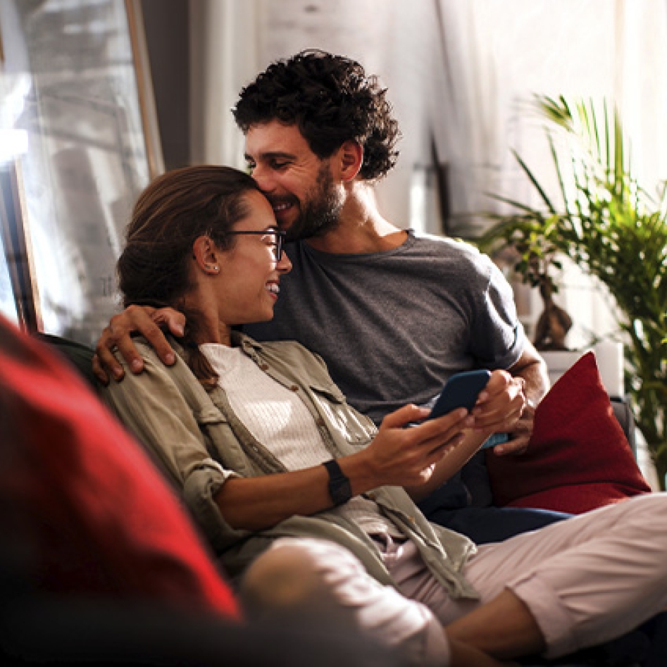 un couple sur leur canapé qui s'embrasse