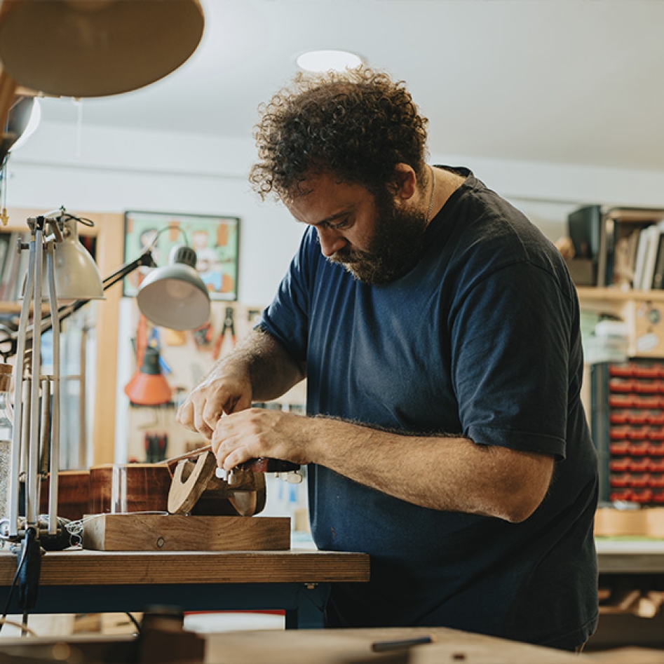 Un homme dans son atelier qui travaille un pièce de bois